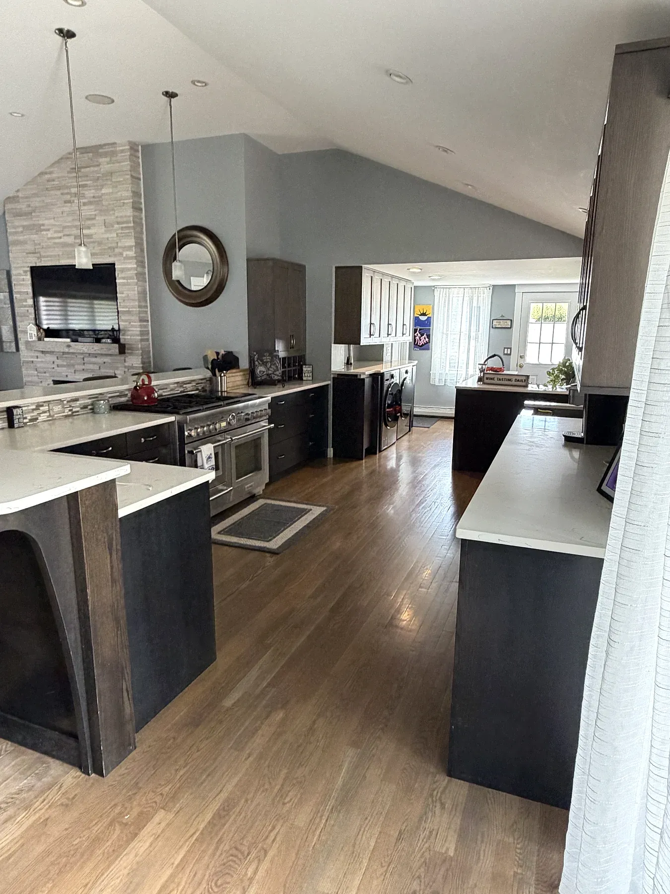 An open residential kitchen with clean counters, appliances and wood floors.