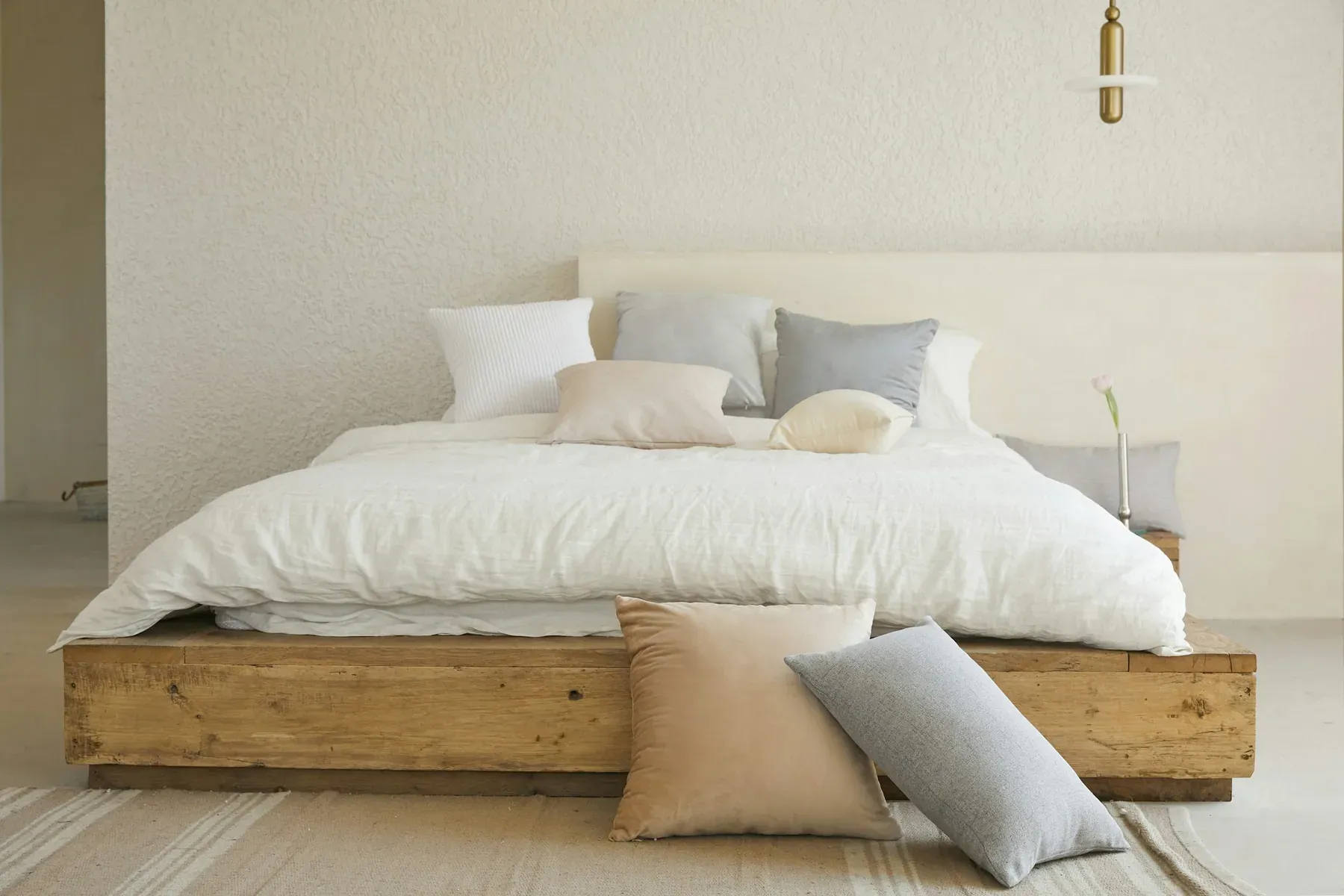A bed made up with crisp white linen in a limewashed room, morning light across the covers.
